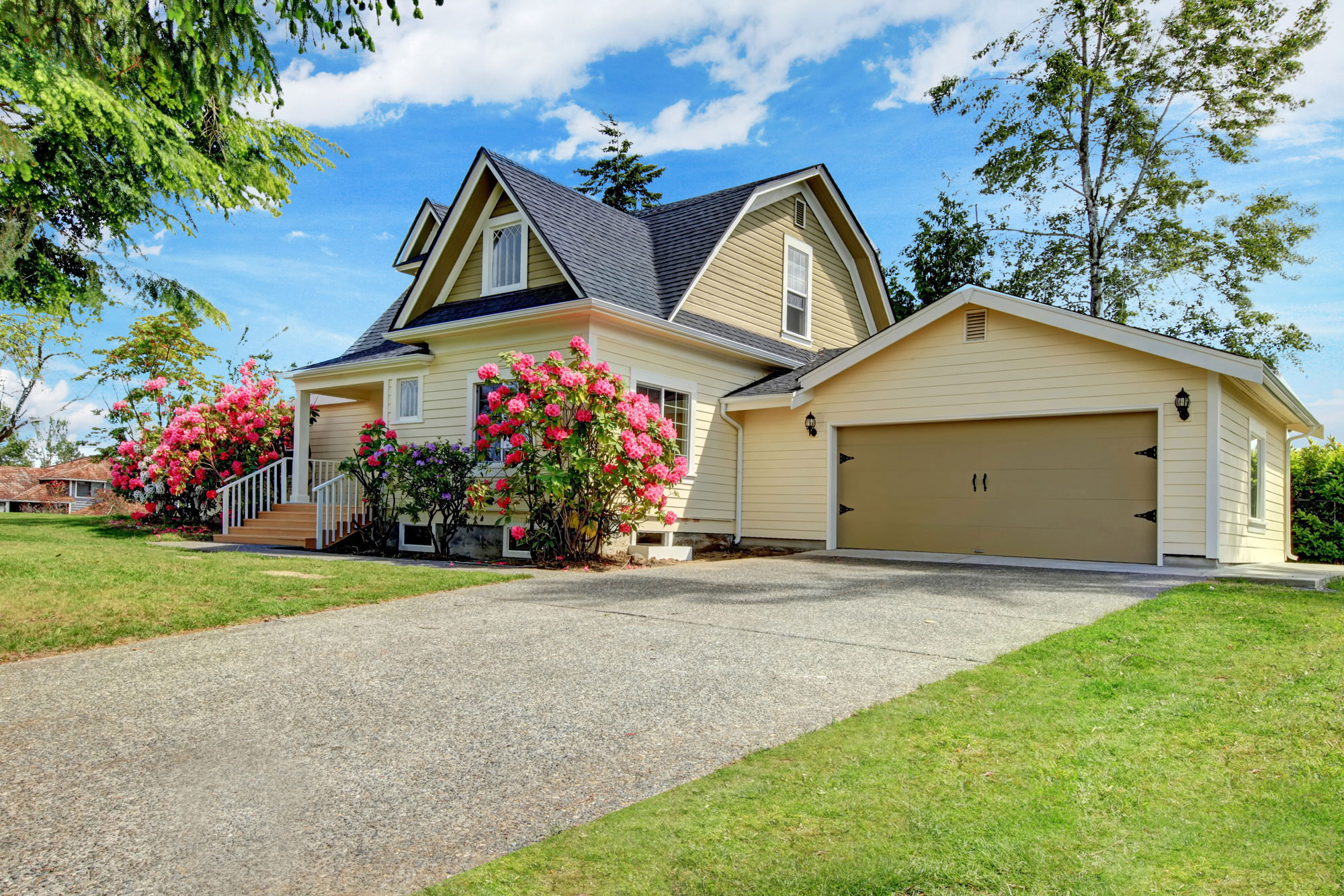 house with yellow siding and pink flowers outside