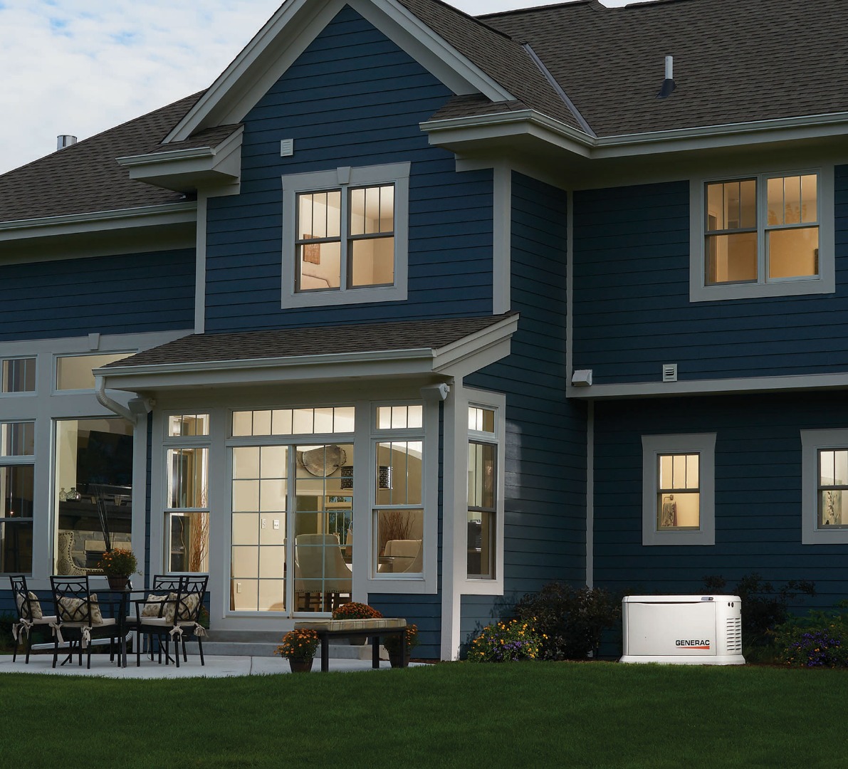 Generac generator outside blue home at night